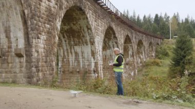 Köprünün altında bir dron teftiş yapıyor. İHA operatörü üst geçitin yanında. Köprü 'yü gözlemlemek için bir kadran. Yol ve köprü bakım teknolojileri. Drone 'lu mühendis. Hava izleme