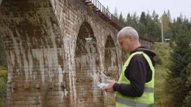 Köprünün altında bir dron teftiş yapıyor. İHA operatörü üst geçitin yanında. Köprü 'yü gözlemlemek için bir kadran. Yol ve köprü bakım teknolojileri. Drone 'lu mühendis. Hava izleme