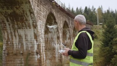 Köprünün altında bir dron teftiş yapıyor. İHA operatörü üst geçitin yanında. Köprü 'yü gözlemlemek için bir kadran. Yol ve köprü bakım teknolojileri. Drone 'lu mühendis. Hava izleme