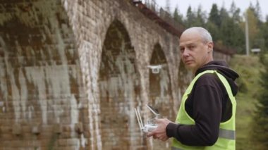Köprünün altında bir dron teftiş yapıyor. İHA operatörü üst geçitin yanında. Köprü 'yü gözlemlemek için bir kadran. Yol ve köprü bakım teknolojileri. Drone 'lu mühendis. Hava izleme