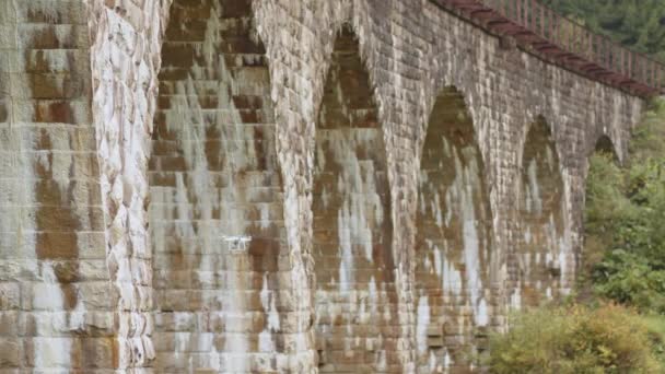 Um drone debaixo de uma ponte a fazer uma inspecção. Inspeção da ponte velha por drone. Inspetores de Segurança Trabalhando na Altura em uma Ponte de Veículo Inspecionando o Concreto para Rachaduras e Danos — Vídeo de Stock