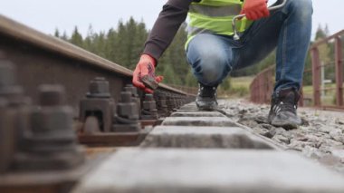 İşçi demiryolunda vidayı sıkılaştırır. Demiryollarında yürüyen ve rayları kontrol eden mühendis. Demiryolu raylarının denetimi ve kontrolü mühendis tarafından gerçekleştirilir. Demiryolunda çalış..