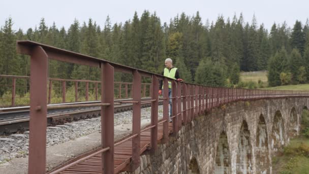 Железнодорожный инженер проверяет железнодорожную линию. Инспекция и контроль железнодорожных путей осуществляется инженером, и все отклонения фиксируются для безопасности транспортировки. Работа на железной дороге — стоковое видео