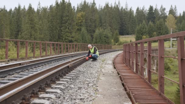 Железнодорожный инженер проверяет железнодорожную линию. Инспекция и контроль железнодорожных путей осуществляется инженером. Работа на железной дороге. Инженерная ходьба и проверка путей на железных дорогах. — стоковое видео