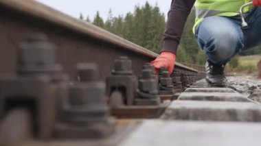 Demiryolunda çalış. İşçi demiryolunda vidayı sıkılaştırır. Demiryollarında yürüyen ve rayları kontrol eden mühendis. Demiryolu raylarının denetimi ve kontrolü mühendis tarafından gerçekleştirilir..