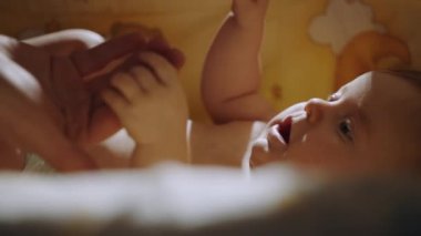Close-up shot of babys little hand reaching for fathers loving finger. Baby holding parents finger. Parent holding newborns hand in Slow Motion. Hand in hand. Father or mother and newborn baby .