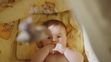 Çocuk Beşiğinde Arkaya Yatan Sevimli Yeni Doğan Bebeğin Güzel Yakın Çekimi. Heyecanlı bir yenidoğan çocuğun oyuncaklara bakışının oyuncu portresi. Çocukluk, Yeni Hayat, Ebeveynlik kavramı.