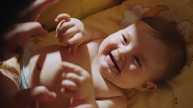 Aile birlikte eğlenir. Anne akşamları kanepede çocukla oynuyor ve konuşuyor. Mutlu bebek iletişimi gülümseyerek öğreniyor. Beşikte gülen mutlu bir bebeğin portresi.