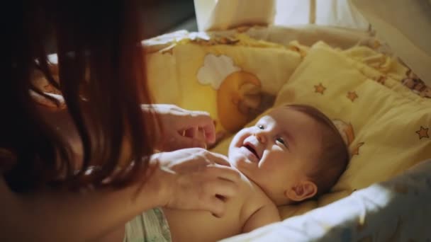 Closeup portrait of a happy baby laughing in crib. Happy family, Mother and child on a bed. Mom and baby are playing. A parent and a small child are resting at home. — Vídeo de stock