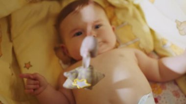 Playful Portrait of an Excited Neonate Toddler Looking at Rotating Toys. Concept of Childhood, New Life. Cute baby lying in his crib. Beautiful Close Up Footage of a Cute Newborn Baby Lying.