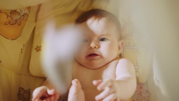 Conceito de Infância, Nova Vida. Bebê bonito deitado em seu berço. Beautiful Close Up Filmagem de um bebê recém-nascido bonito mentindo. Retrato lúdico de uma criança animada Neonate Olhando para brinquedos rotativos — Vídeo de Stock