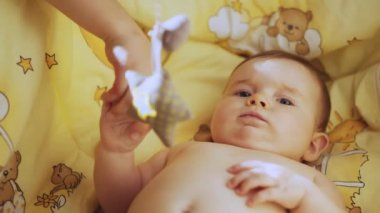Close Up Footage of Newborn Baby Playing With Mothers Hand and Finger while Lying on the Back in Child Crib. Authentic Close Up Footage of a Cute Newborn Baby Lying on the Back in Child Crib.