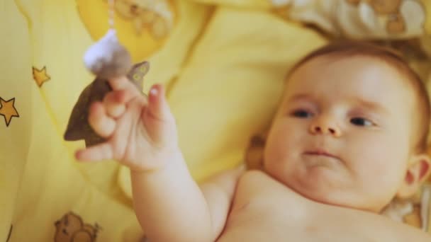 Conceito de Infância, Nova Vida. Imagens autênticas de um bebê recém-nascido bonito deitado de costas no berço da criança. Retrato lúdico de uma criança animada Neonate Olhando para brinquedos rotativos. — Vídeo de Stock