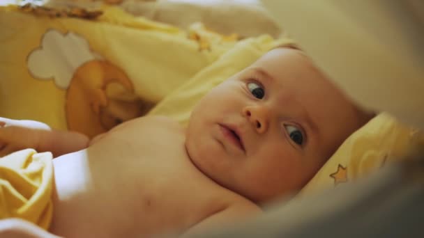 Authentische Nahaufnahme eines niedlichen Neugeborenen, das auf dem Rücken in einem Kinderbett liegt. Verspieltes Porträt eines kaukasischen Neugeborenen. Konzept von Kindheit, neuem Leben und Elternschaft. Kind in der Wiege. — Stockvideo