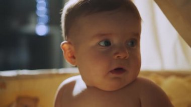 Akşamları beyaz ahşap karyolada duran bebek, gece lambasının ışığında mutlu erkek bebek yüzü. Çocukluk kavramı, yeni hayat, ebeveynlik. Karanlık Oda