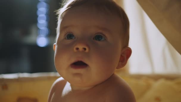 Baby standing in white wooden crib in the evening, face of happy baby boy in light of night lamp. Concept of Childhood, New Life, Parenthood. Cute little toddler child standing in crib in the evening. — Stockvideo