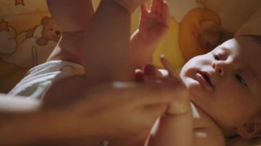 Concept of Childhood, New Life and Parenthood. Close Up Footage of Newborn Baby Playing With Mothers Hand and Finger while Lying on the Back in Child Crib. Caucasian Neonate Toddler Bonding with Mom