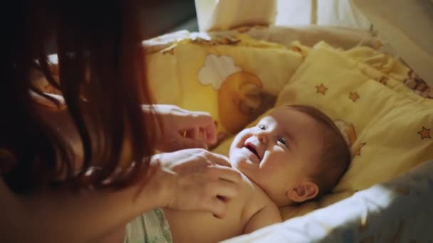 一个在婴儿床里笑的快乐婴儿的画像 幸福的家庭 母亲和孩子在床上 妈妈和宝宝在玩耍 一个父母和一个小孩在家里休息 — 图库视频影像