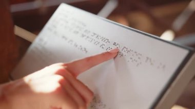 Hands of a Blind reading Braille. Close Up. The hand of a blind man reads the text of a braille book. Braille book