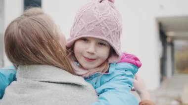 Genç anne, çocuk, kız sonbaharda parkta sarılıyorlar. Çocuk, kız, sevgi dolu anne sokakta sarılıyor. Çocuk gülümsüyor ve annesine sarılıyor. Yakın plan. Mutlu aile, anne, yaz parkında çocuk kucaklaşması.