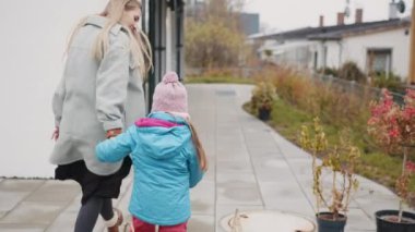 Kız annesiyle tanıştığı için mutlu. Anne, çocukluk. Mutlu aile, anne ve kız el ele tutuşun. Çocuk, annenin elini tutan kız, evin yakınında bir aile. Mutlu aile, çocuk yürüyüşü.
