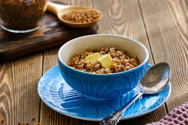 Taze ve lezzetli karabuğday lapası, ahşap bir masada mavi bir fincanda tereyağlı.