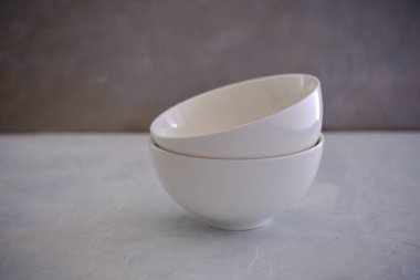 Beton bir masanın üzerinde kasesi olan beyaz seramik bir tabak.