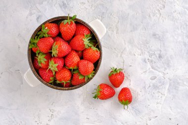 Sulu, parlak ve tatlı çilekler yakın plan beyaz beton bir masada bir kasede.