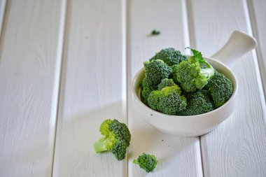 Taze yeşil brokoli beyaz kâse içinde açık masa üzerinde vejetaryen yemeği.