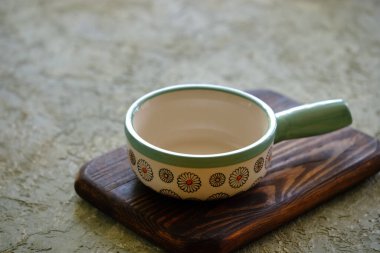 Seramik kâse, beton bir masanın üzerinde ahşap bir sapla yakın plan.