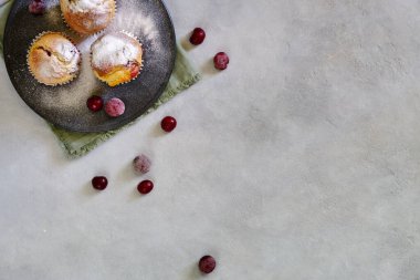 Kirazlı mis kokulu limonlu kekler, siyah bir tabakta, yakın plan gri bir fonda.