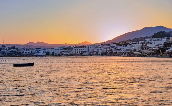 12 Temmuz 2022, Türkiye, Bodrum, şehir plajı. İnsanlar sahildeki masalarda oturup gün batımını seyrediyorlar. Gece manzarası