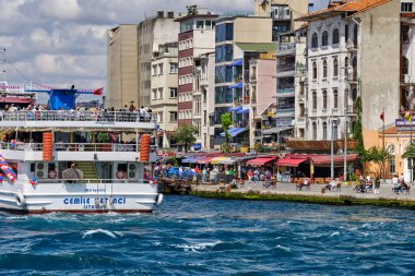 İstanbul, Türkiye - 19 Temmuz 2022, Karaköy İskelesi ve kentin Avrupa bölgesi, rıhtıma yolcu taşıyan feribotlar, insanlar Boğaz seti boyunca yürüyor.