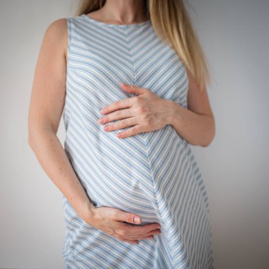 Hamile bir kadın elleri karnında durur, bebek beklemesi konsepti...