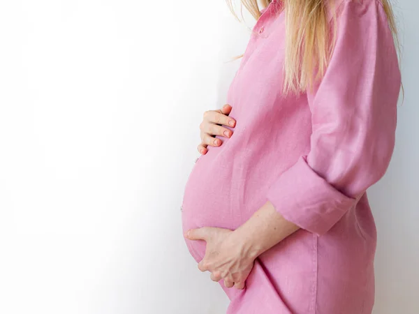 Een zwangere vrouw staat met haar handen op haar buik, het concept van het verwachten van een baby — Stockfoto