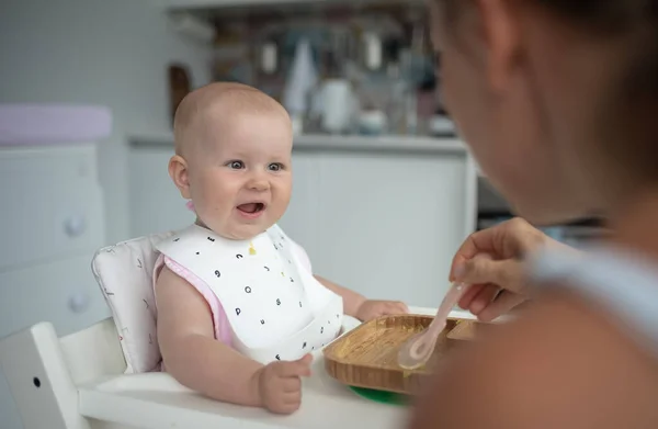 Primera alimentación de los bebés, mamá alimenta a un bebé con una cuchara Imagen De Stock