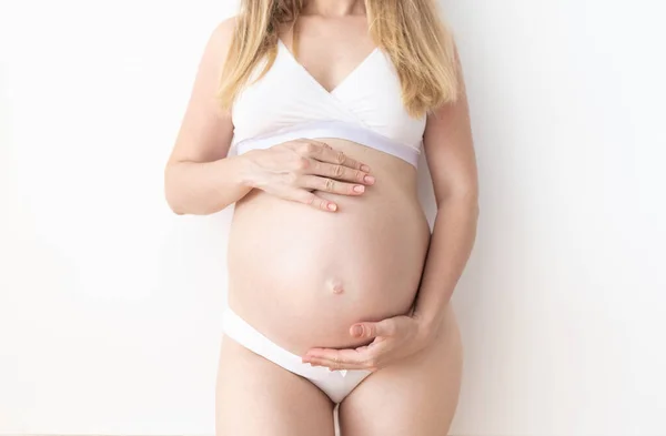 Těhotná žena stojící drží ruce na břiše — Stock fotografie