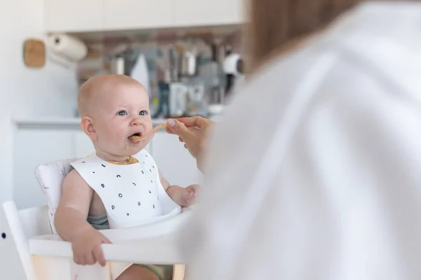 První krmení dítěte, matka krmí dítě v kuchyni Royalty Free Stock Obrázky