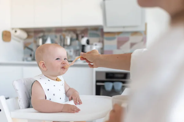 Primera alimentación de los bebés, mamá alimenta a un bebé con una cuchara Imagen De Stock