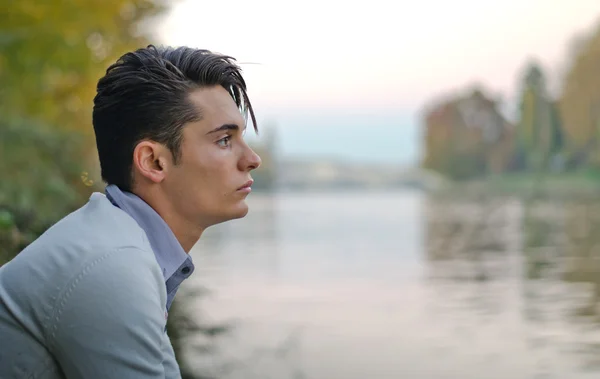 Good looking young man outdoors in nature (river, lake, trees) — Stock Photo, Image