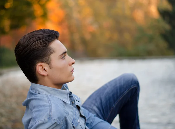 Belo modelo masculino jovem na lagoa ou lago no outono — Fotografia de Stock