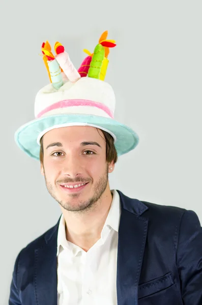 Smiling, cute guy with funny birthday cake hat — kuvapankkivalokuva