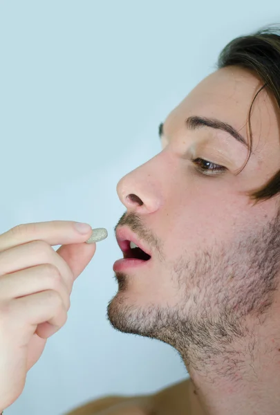 Beau jeune homme prenant la pilule ou médecine capsule — Photo