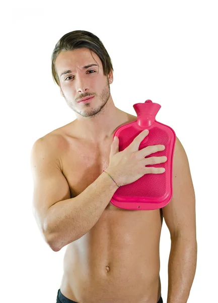 Handsome young man with shoulder pain, holding hot water bottle — Stock Photo, Image