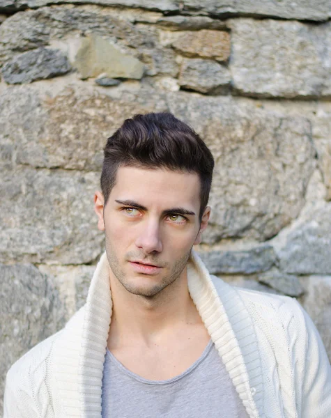 Porträtt av attraktiv ung man utomhus mot stenmur — Stockfoto