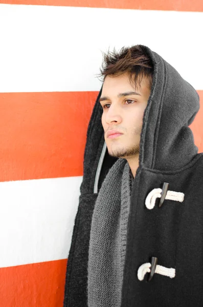 Attractive young man in hoodie against white and orange wall — Stock Photo, Image