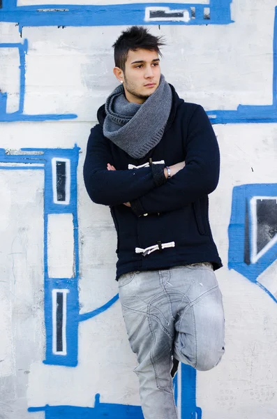 Handsome young man standing against graffiti covered wall — Stock Photo, Image