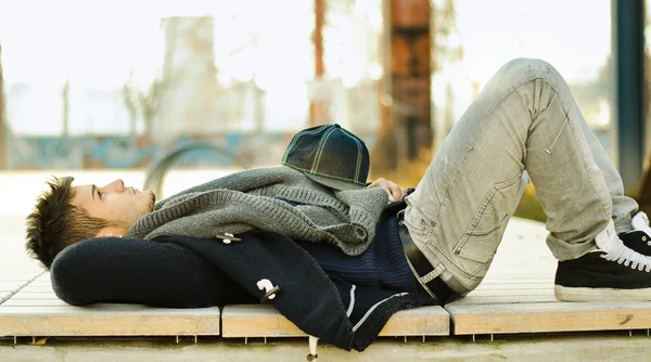 Attractive young man laying on bench — Stock Photo, Image