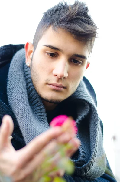 Jovem atraente olhando para flor — Fotografia de Stock