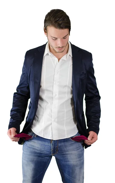 Broke young man looking at empty pockets — Stock Photo, Image